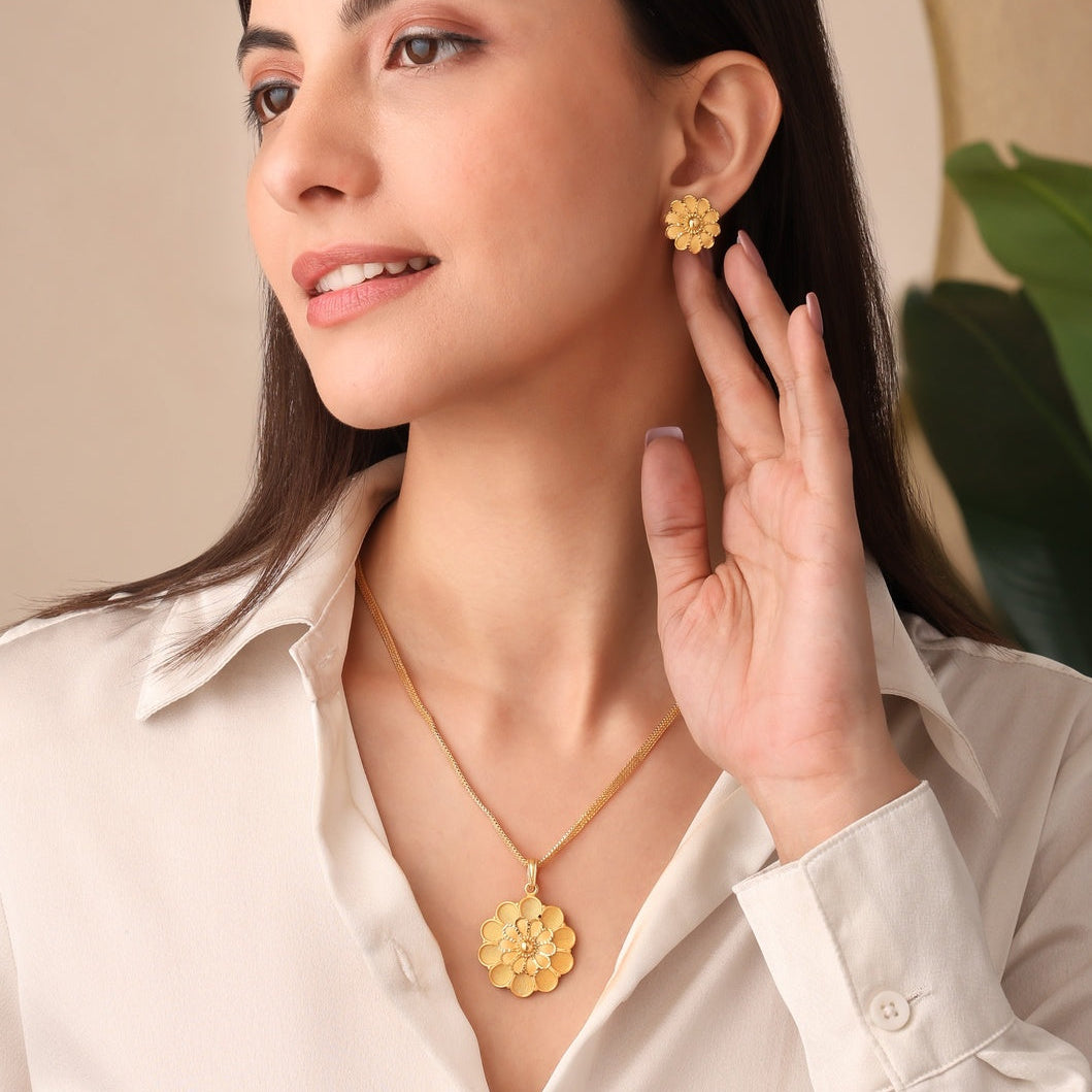 Woman wearing gold earrings and necklace, holding hand to ear