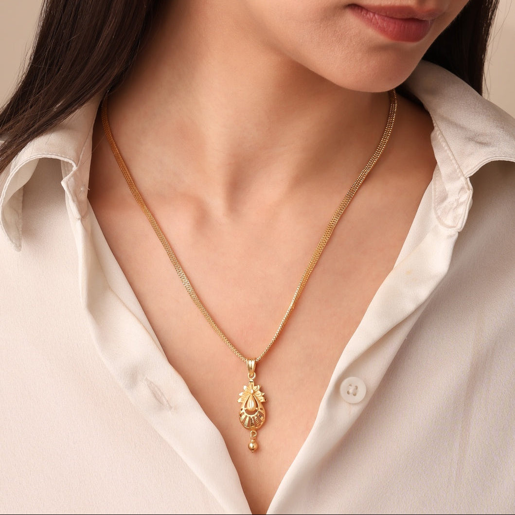 Woman wearing a gold necklace and earrings against a neutral background