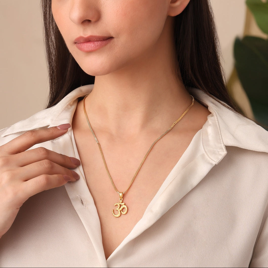 Woman wearing a gold necklace with a pendant, posing against a neutral background