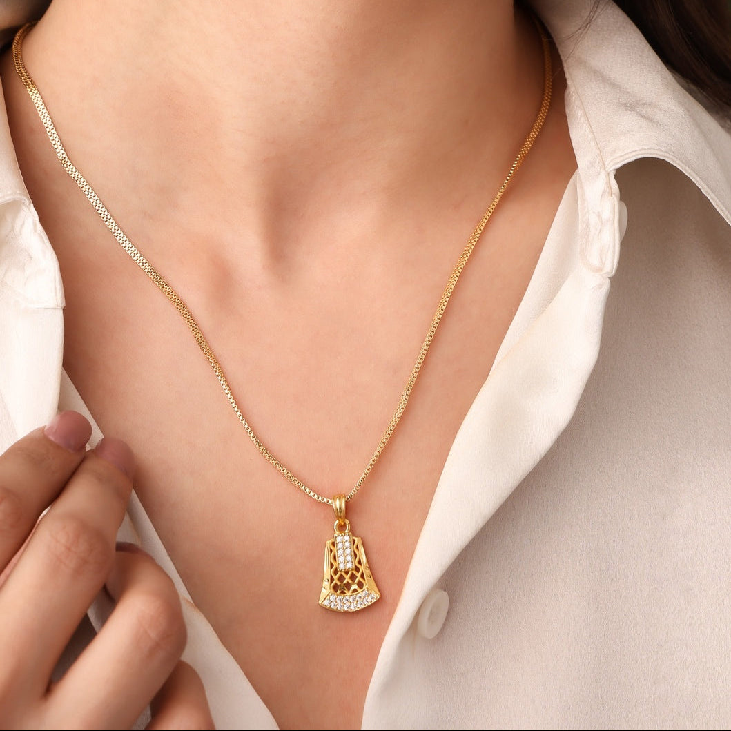 Gold necklace with a pendant worn by a person against a neutral background