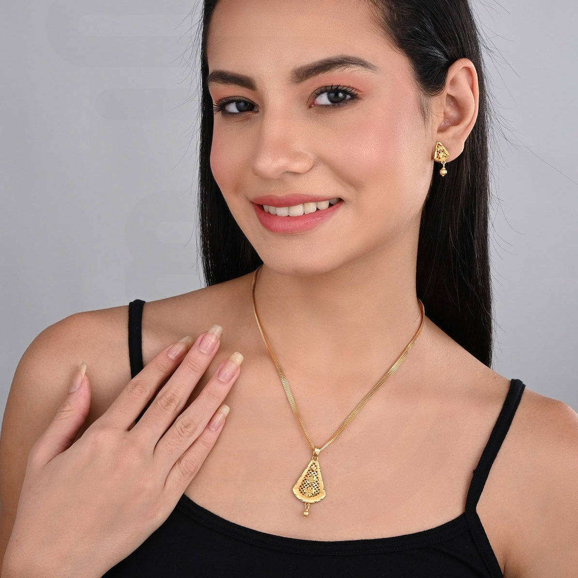 Woman wearing gold necklace and earrings on a gray background