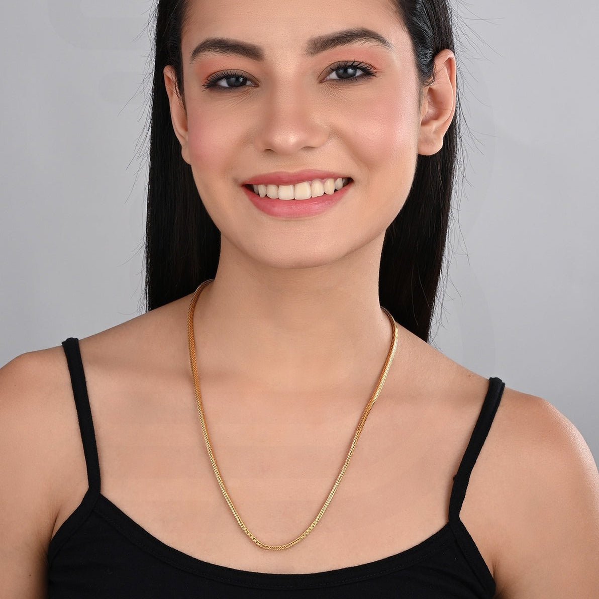 Woman wearing a gold necklace against a gray background