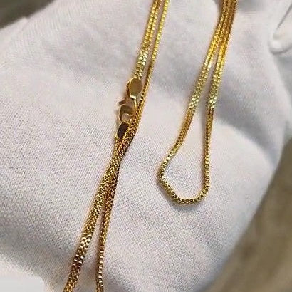 Gold chain necklace on a white cushion