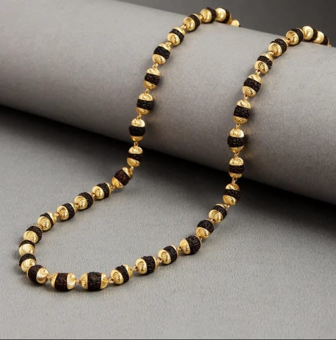 Necklace with gold and black beads on a gray surface